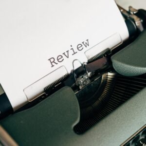Close-up of an antique typewriter printing the word 'Review' on white paper.